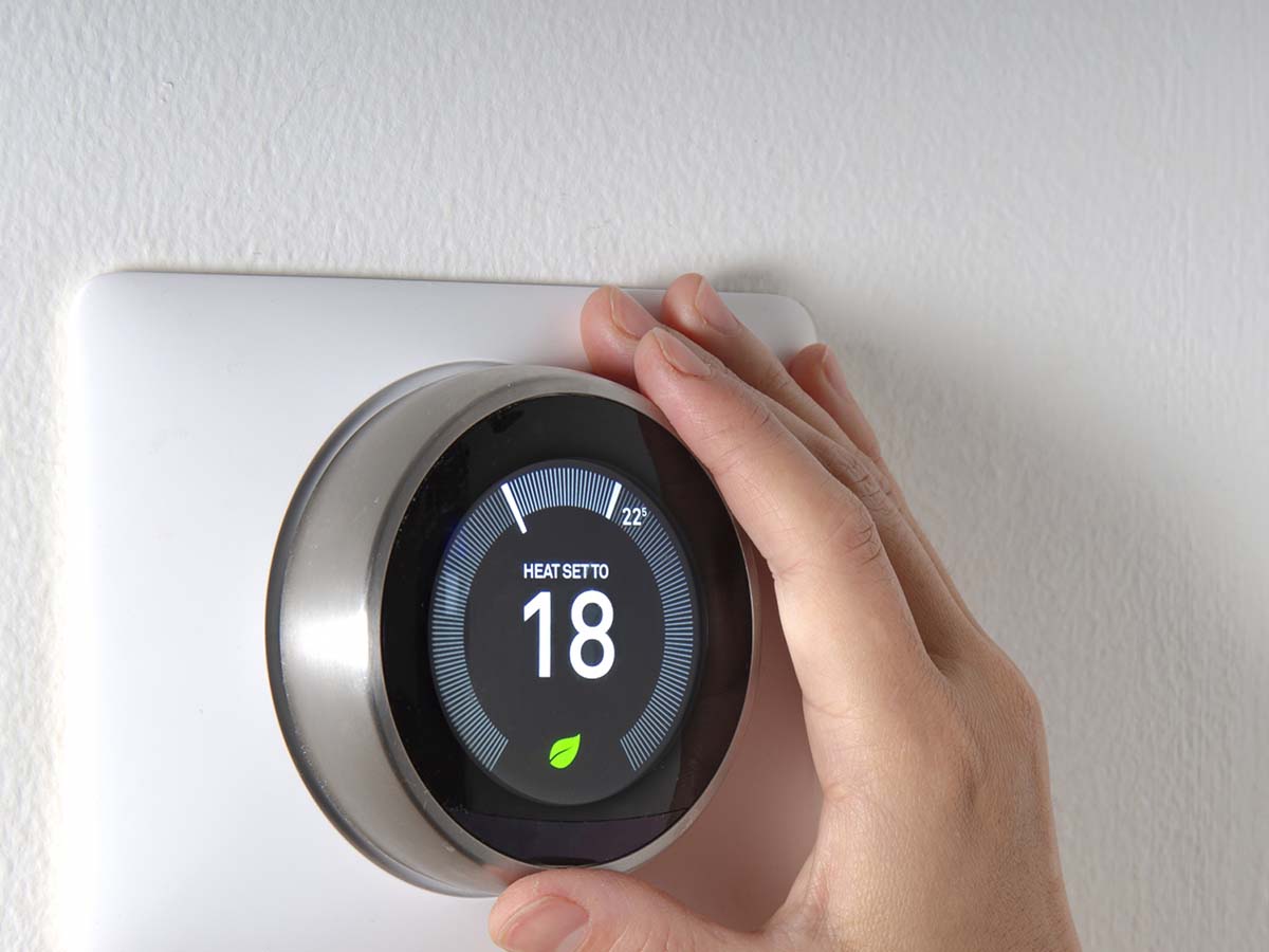 An image of someone setting a smart thermostat.